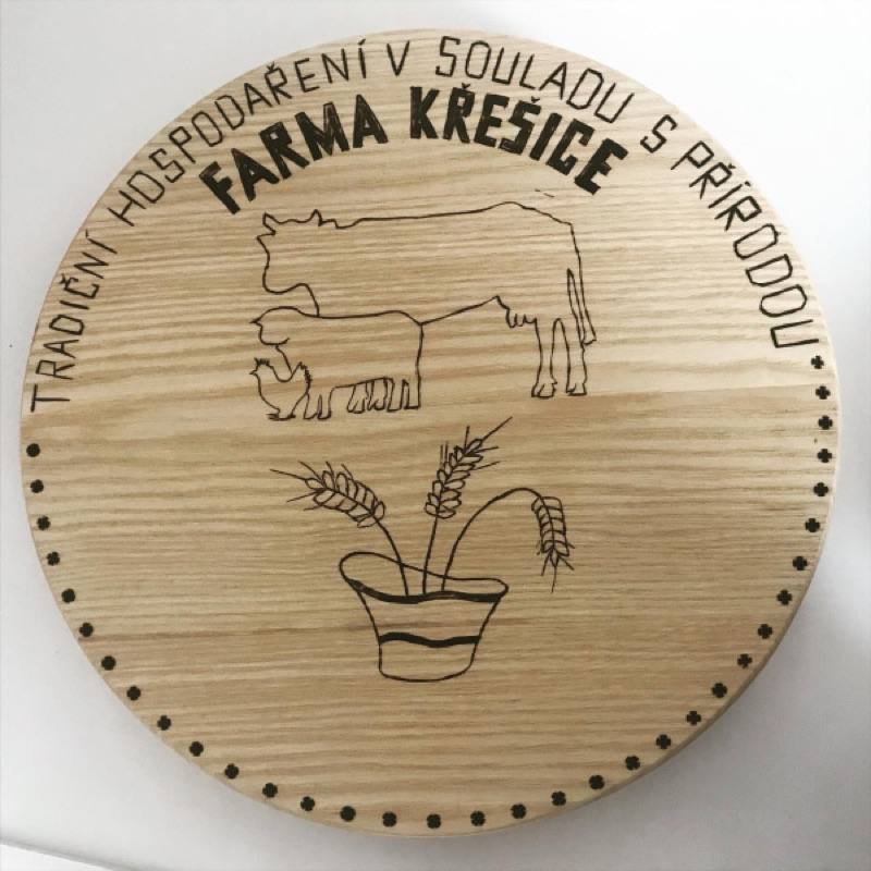 Dřevěné logo Farmy Křešice s mottem Tradiční hospodaření v souladu s přírodou