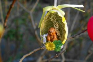 otevřená velikonoční kraslice se slámou, zajíčkem a květinami