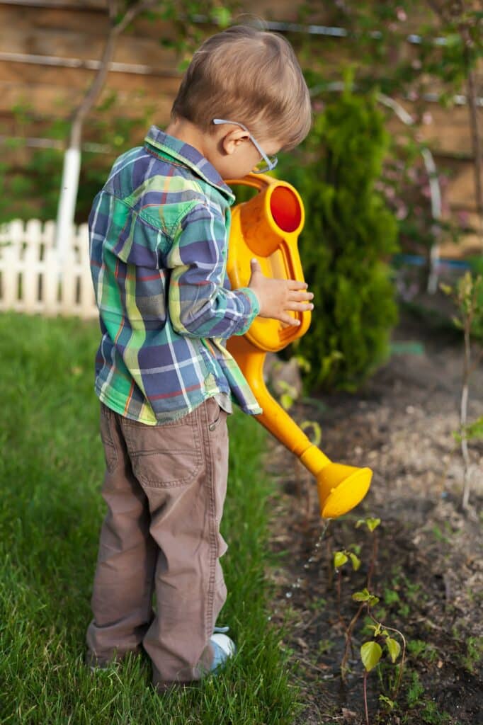 Zalévání 4 Child watering can watering a garden in the backyard