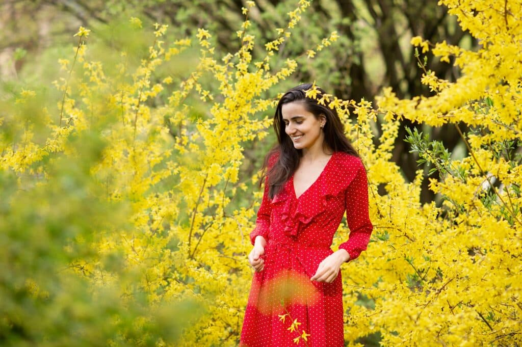 forzýtie- rostoucí v hojném počtu a stojící dáma v červených šatech u prostřed.