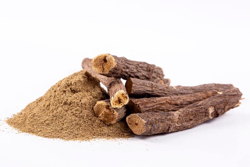 Lékořice a lékořicový prášek na bílém pozadí