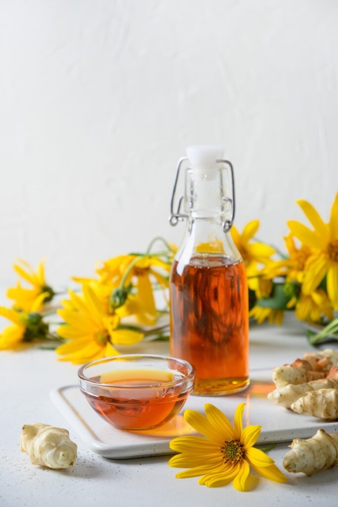 Sirup z topinamburu v lahvi, doplněný květy a hlízou